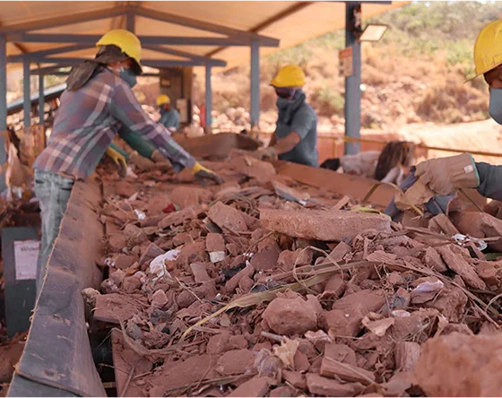 Trabalhadores realizando a triagem de resíduos de construção em esteira coberta